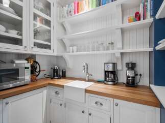 Discover a charming kitchen space featuring white shaker cabinets and a beautiful butcher block countertop.