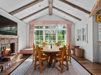 Experience rustic charm in this dining room featuring exposed wooden beams and a cozy brick fireplace.