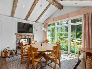 Experience rustic charm in this dining area, featuring exposed wooden beams and a cozy brick fireplace.
