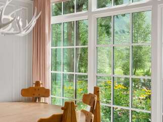 Experience breathtaking natural beauty from this home, featuring expansive windows that frame a vibrant garden and lush mountain views.