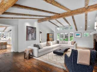 Experience rustic charm and modern comfort in this spacious living room, featuring exposed wooden beams and a large sectional sofa perfect for gatherings.