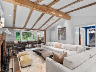 Experience rustic elegance in this spacious living area, featuring exposed wooden beams and a grand brick fireplace.
