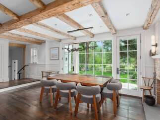 Experience rustic charm and modern elegance in this stunning dining room, featuring exposed wooden beams and a grand fireplace.