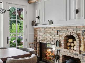 Experience cozy evenings by the crackling fireplace in this charming dining area, featuring a rustic brick hearth and a well-stocked wood nook.