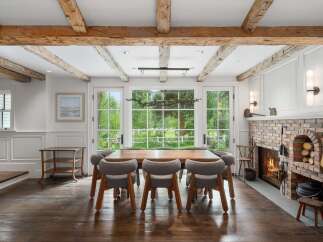 Experience rustic charm in this dining room featuring exposed wooden beams and a cozy brick fireplace.