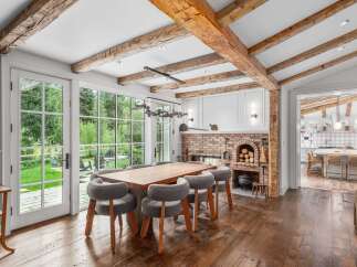 Experience rustic charm and modern elegance in this stunning dining room, featuring exposed wooden beams and a grand brick fireplace.