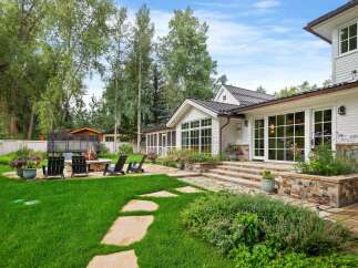 Experience outdoor living at its finest with this beautifully landscaped backyard, featuring a cozy fire pit area perfect for gatherings and a lush green lawn ideal for recreation.