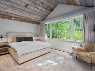 Experience ultimate comfort in this serene bedroom, featuring a plush king-sized bed adorned with crisp white linens and dark accent pillows.