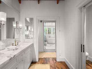 Experience luxury in this stunning bathroom featuring a spacious double vanity with a marble countertop and elegant brass fixtures.