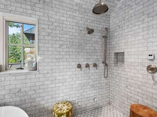 Experience luxury in this stunning bathroom featuring a spacious marble subway tile shower with multiple shower heads and a built-in niche.