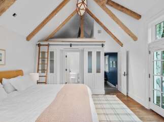 Experience rustic charm and modern comfort in this stunning bedroom featuring exposed wooden beams and a vaulted ceiling.