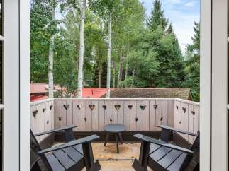 Enjoy the serene mountain views from this charming balcony, featuring two comfortable Adirondack chairs and a small bistro table.