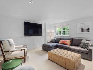 This inviting living room features a spacious sectional sofa complemented by a stylish woven ottoman and a comfortable armchair.