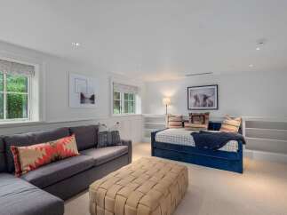 This inviting living space features a comfortable sectional sofa adorned with decorative pillows, complemented by a woven ottoman for added texture.