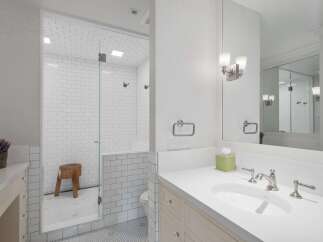Experience luxury in this beautifully appointed bathroom, featuring a spacious walk-in shower with classic subway tile and a sleek glass enclosure.