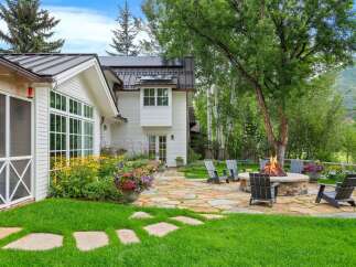 Experience outdoor living at its finest with this charming backyard oasis, featuring a cozy fire pit area perfect for gatherings and a lush green lawn.