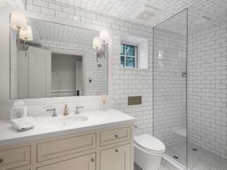 This modern bathroom features a sleek white vanity with a quartz countertop, complemented by a large mirror and elegant wall sconces.