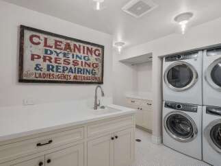 This spacious laundry room boasts a stacked Electrolux washer and dryer set, perfect for handling large loads.
