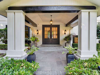 Step into luxury with this stunning home featuring a grand entrance framed by elegant white pillars and a dark wood double door.