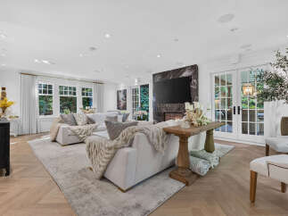 Experience luxurious living in this spacious great room, featuring a modern marble fireplace and a large flat-screen TV.