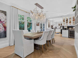Experience elegant dining in this beautifully appointed space, featuring a large wooden table surrounded by plush white chairs.