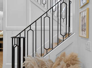 Experience elegant living with this stunning staircase featuring a modern black metal railing and intricate geometric accents.