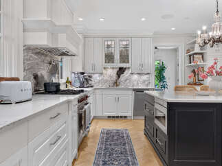 Experience culinary excellence in this stunning chef's kitchen, featuring sleek white cabinetry, luxurious marble countertops, and a professional-grade gas range.