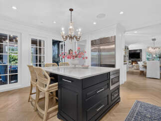 Experience luxury living in this stunning kitchen, featuring a large island with seating, a built-in microwave, and sleek cabinetry.