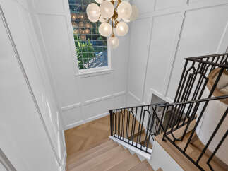 Ascend in style on this elegant staircase featuring light wood flooring laid in a herringbone pattern.