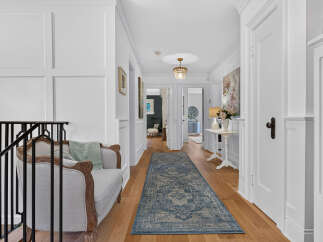 Step into this elegant hallway, featuring a classic wainscoting design and a beautiful hardwood floor.