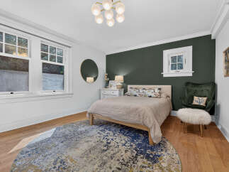 Discover this charming bedroom featuring a plush green armchair and a stylish round rug.