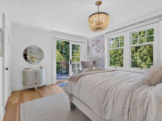 Experience serene living in this charming bedroom, featuring a plush bed adorned with a soft throw and a decorative pillow.