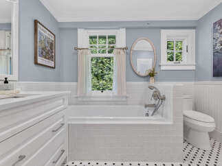 This beautifully renovated bathroom features a classic white subway tile tub surround and a sleek white vanity with ample storage.