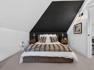 Experience modern comfort in this stylish bedroom featuring a striking black accent wall that adds a dramatic flair.