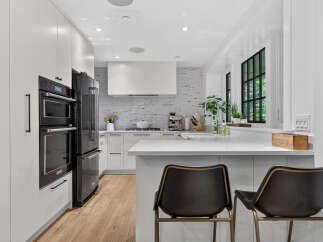 Experience modern luxury in this stunning kitchen, featuring sleek white cabinetry, integrated double ovens, and a professional-grade refrigerator.