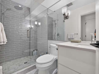 Experience modern luxury in this stunning bathroom featuring a spacious glass-enclosed shower with dual showerheads and elegant grey subway tile.