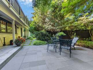 Enjoy outdoor living in this charming backyard oasis, featuring a spacious stone patio perfect for entertaining.
