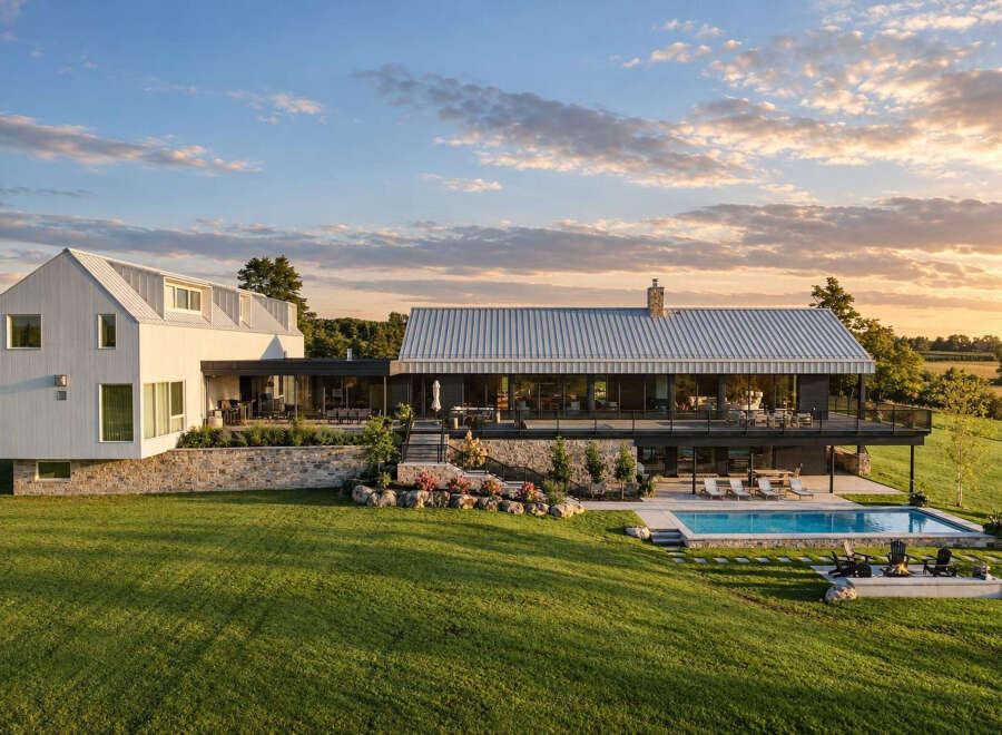 Experience luxury living in this stunning modern farmhouse, featuring a sleek white exterior and a durable metal roof.