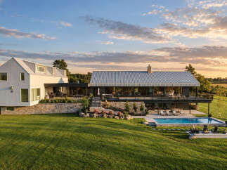 Experience luxury living in this stunning modern farmhouse, featuring a sleek white exterior and a durable metal roof.