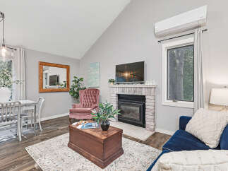 Experience cozy living in this inviting space, featuring a charming brick fireplace and a large flat-screen TV perfect for entertainment.