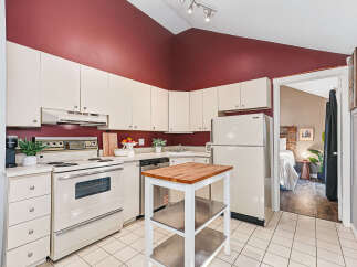 Discover this charming kitchen featuring cream-colored cabinetry and a striking burgundy accent wall.