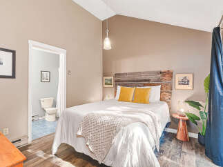 Experience comfort and style in this charming bedroom featuring a rustic wooden headboard and plush yellow accent pillows.