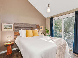 Experience serene living in this charming bedroom featuring a rustic wooden headboard and a plush white duvet.