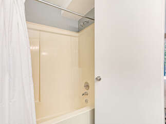 Step into this inviting bathroom featuring a classic cream-colored bathtub and shower combination, complete with a sleek chrome showerhead and faucet.