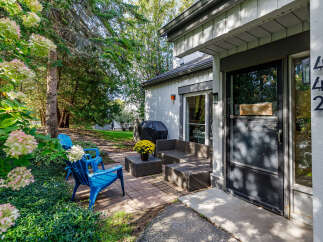 Enjoy outdoor living with this charming patio featuring two bright blue Adirondack chairs and a wicker coffee table adorned with yellow mums.