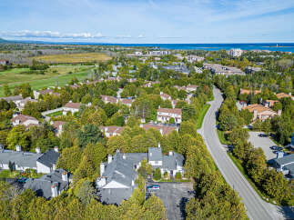 Discover this charming aerial view of a suburban neighborhood, showcasing a cluster of townhouses nestled amongst lush green trees.