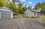 Discover this stunning property featuring a modern gray-sided home with stone accents, complemented by a detached garage and a charming carport.
