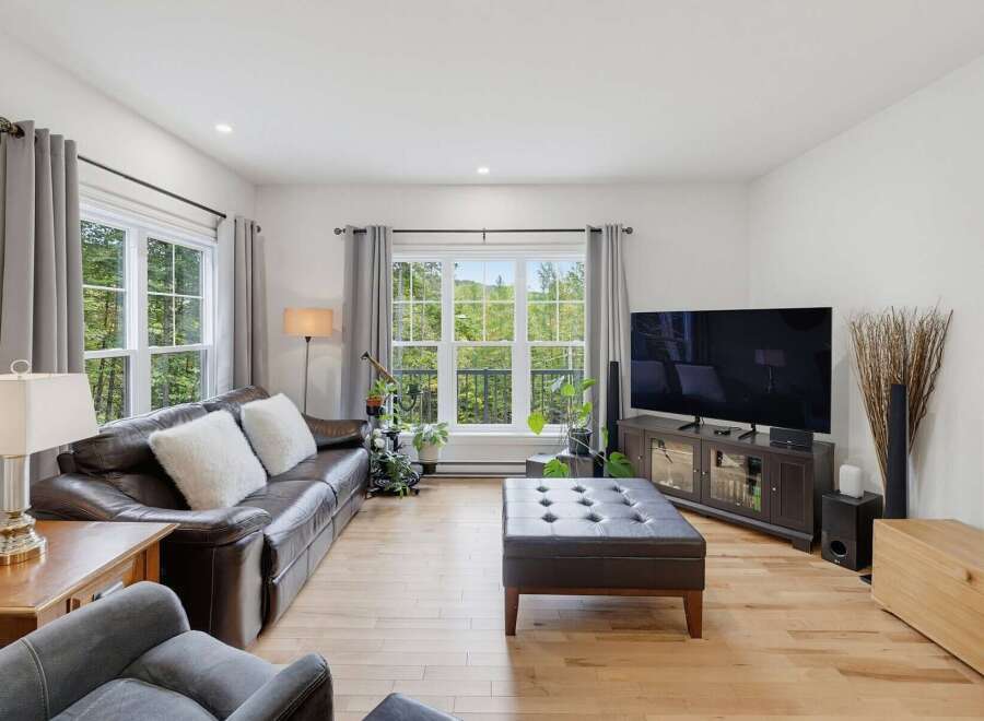 Experience breathtaking natural views from this stunning living room, featuring a comfortable leather sofa and a large ottoman perfect for relaxation.