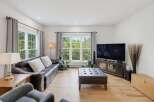 Experience breathtaking natural views from this stunning living room, featuring a comfortable leather sofa and a large ottoman perfect for relaxation.