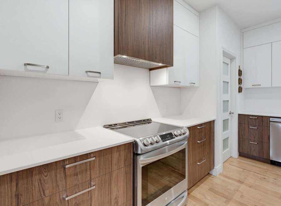 Experience modern living in this stunning kitchen, featuring sleek white cabinetry contrasted with rich wood accents.